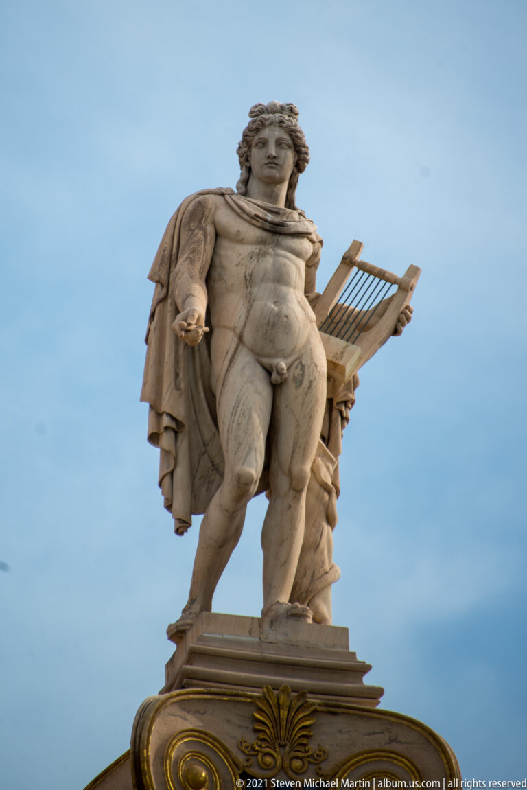Apollo statue with a lyre standing atop a monumental Ionic column at the Academy of Athens.