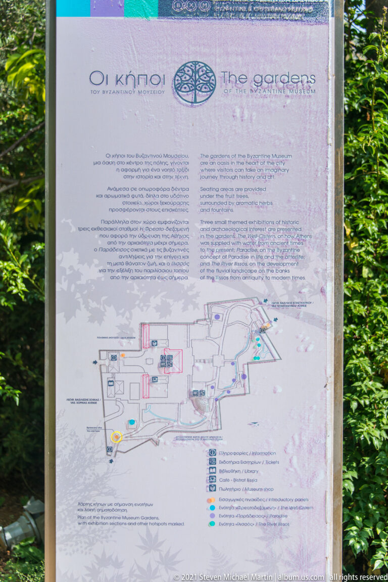 Outdoor bilingual garden interpretation panel with explanatory text and a mapped plan of paths and archaeological areas.