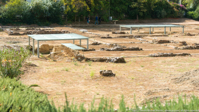 Closer view of shallow stone wall traces and protected remains across dry ground at the Lykeion archaeological site.