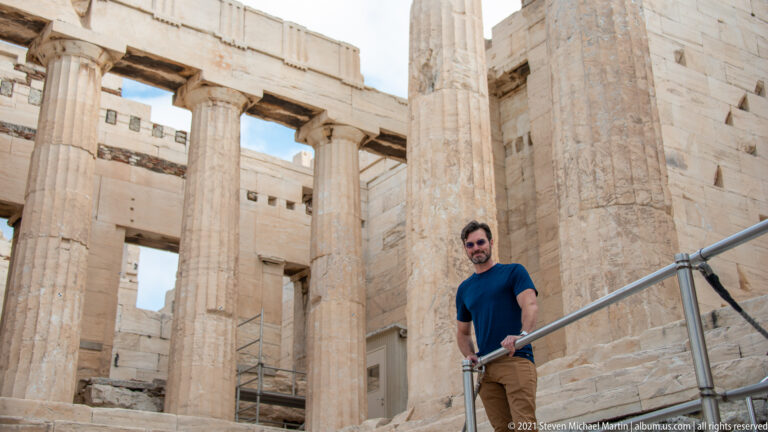 Male visitor beside fluted marble columns and block walls inside the Propylaea.