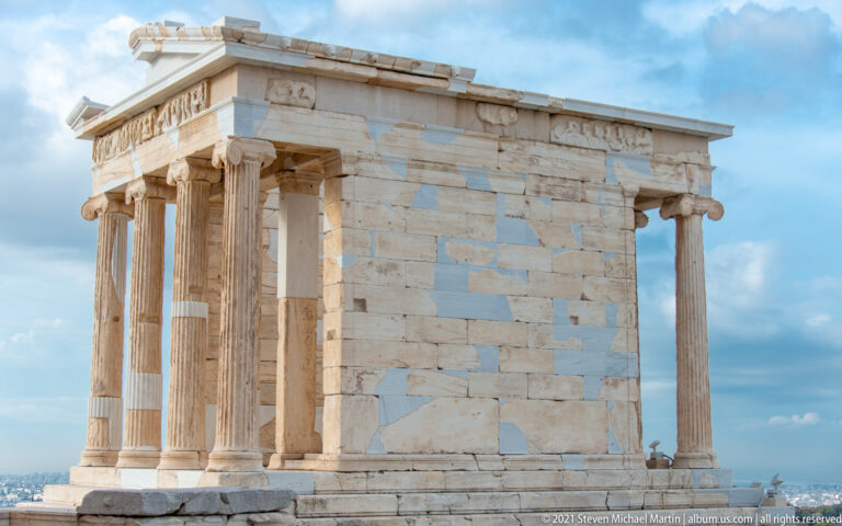 Compact Ionic Temple of Athena Nike in side view, with slender columns, cella wall, and restored marble blocks.