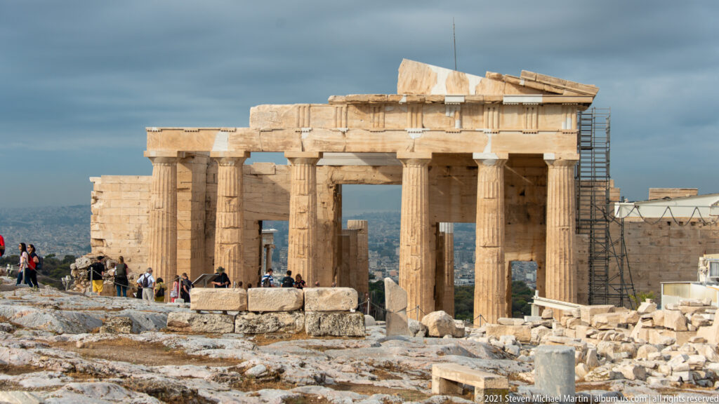 View of the Propylaea on the Acropolis with large Doric columns, central openings, visitors, and scaffolding along one side.