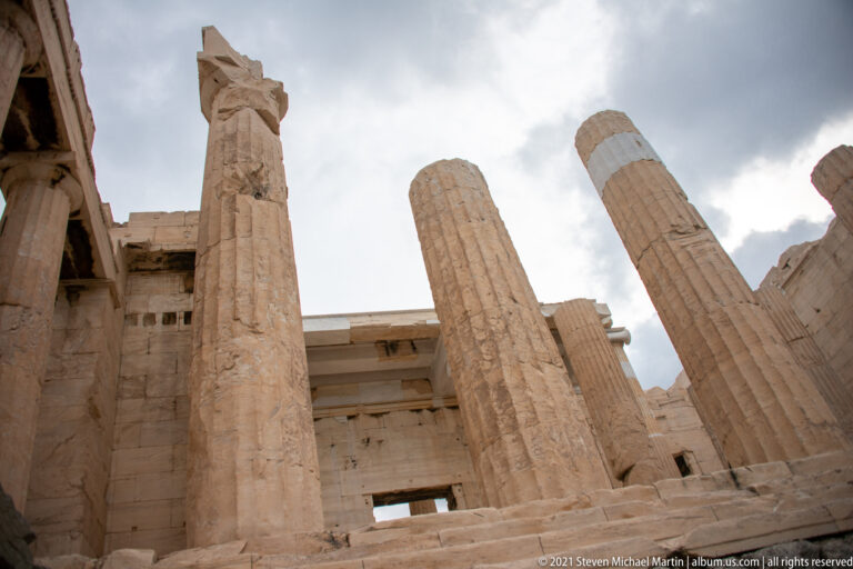 Low-angle view through tall fluted Doric columns and surviving beams of the Propylaia.