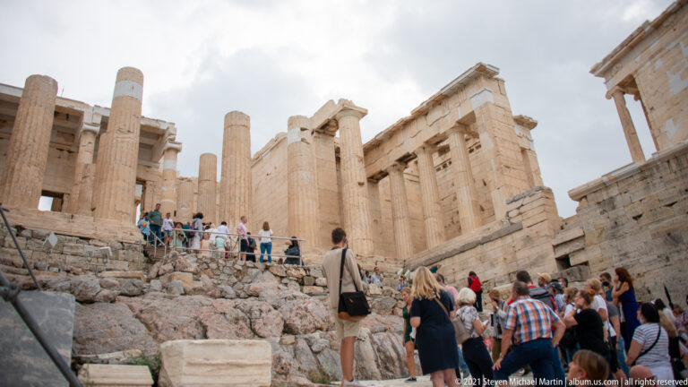 Visitors climb among massive marble columns and walls at the Propylaia entrance to the Acropolis.
