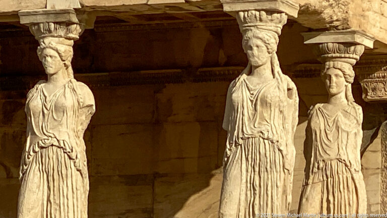 Close sunlit view of three Caryatid copies supporting the south porch of the Erechtheion.