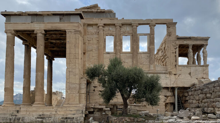 Erechtheion with Ionic columns, olive tree in front, and Caryatid porch visible at the right.