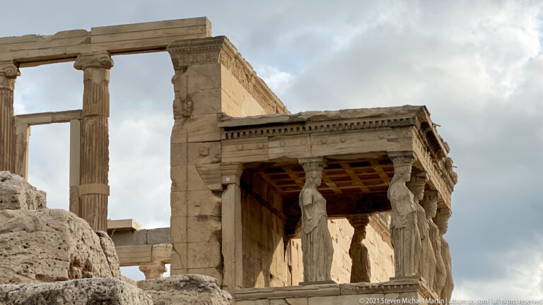 South porch of the Erechtheion with Caryatid copies above rough Acropolis bedrock.