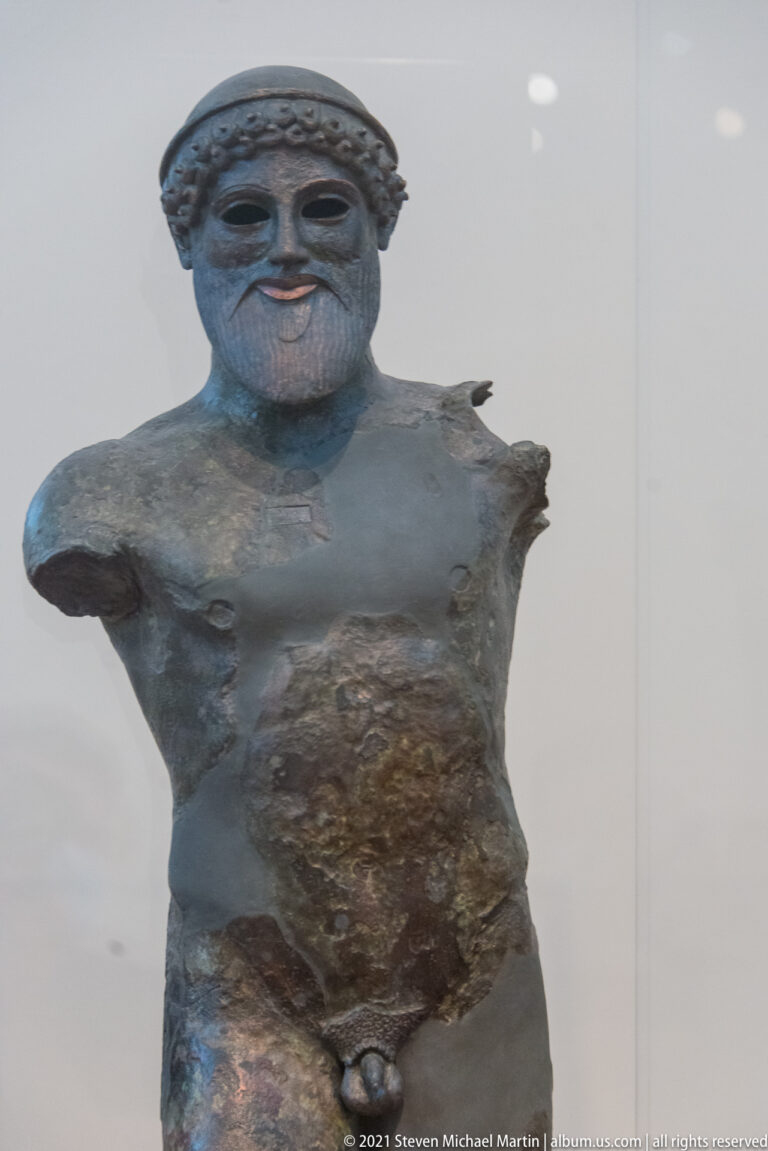 Close view of the bearded bronze Zeus or Poseidon of Artemision, showing the head, muscular torso, and dark ancient patina.