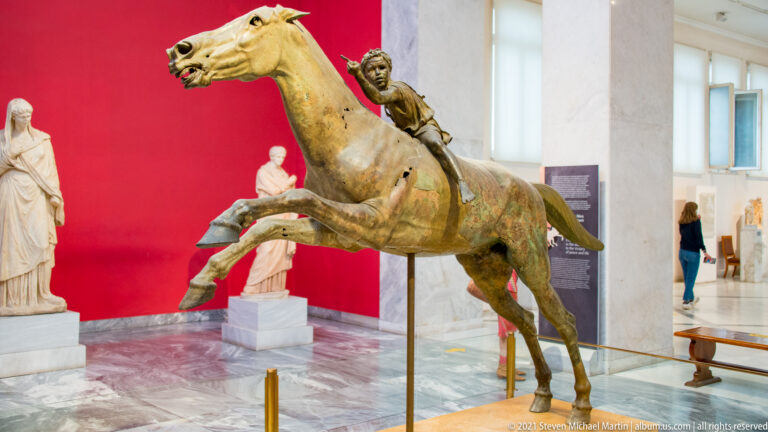 Jockey of Artemision bronze group with a galloping horse and small young rider leaning forward on its back.