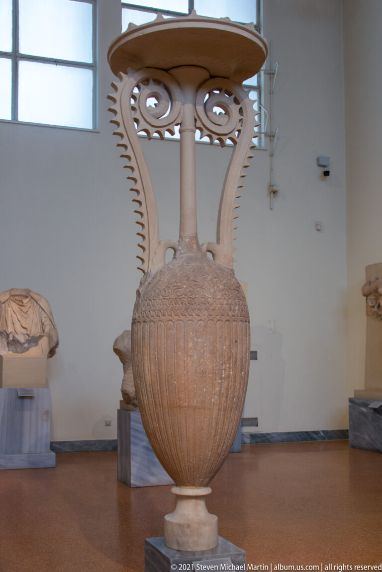 Tall monumental ribbed vessel with elongated openwork spiral handles and a broad disk-like top.