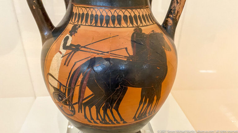 Black-figure vase detail showing several horses harnessed to a chariot with human figures above and behind them.