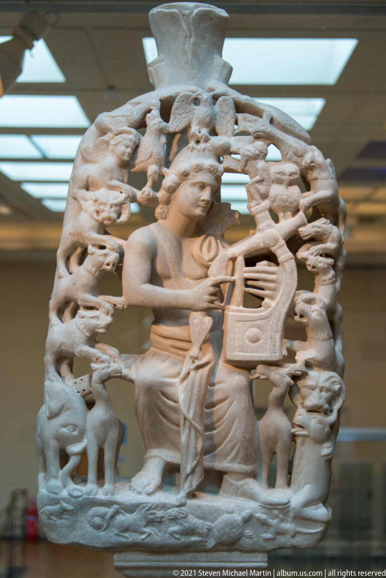Fourth-century marble table support from Aegina showing seated Orpheus playing a lyre amid carved animals and birds.