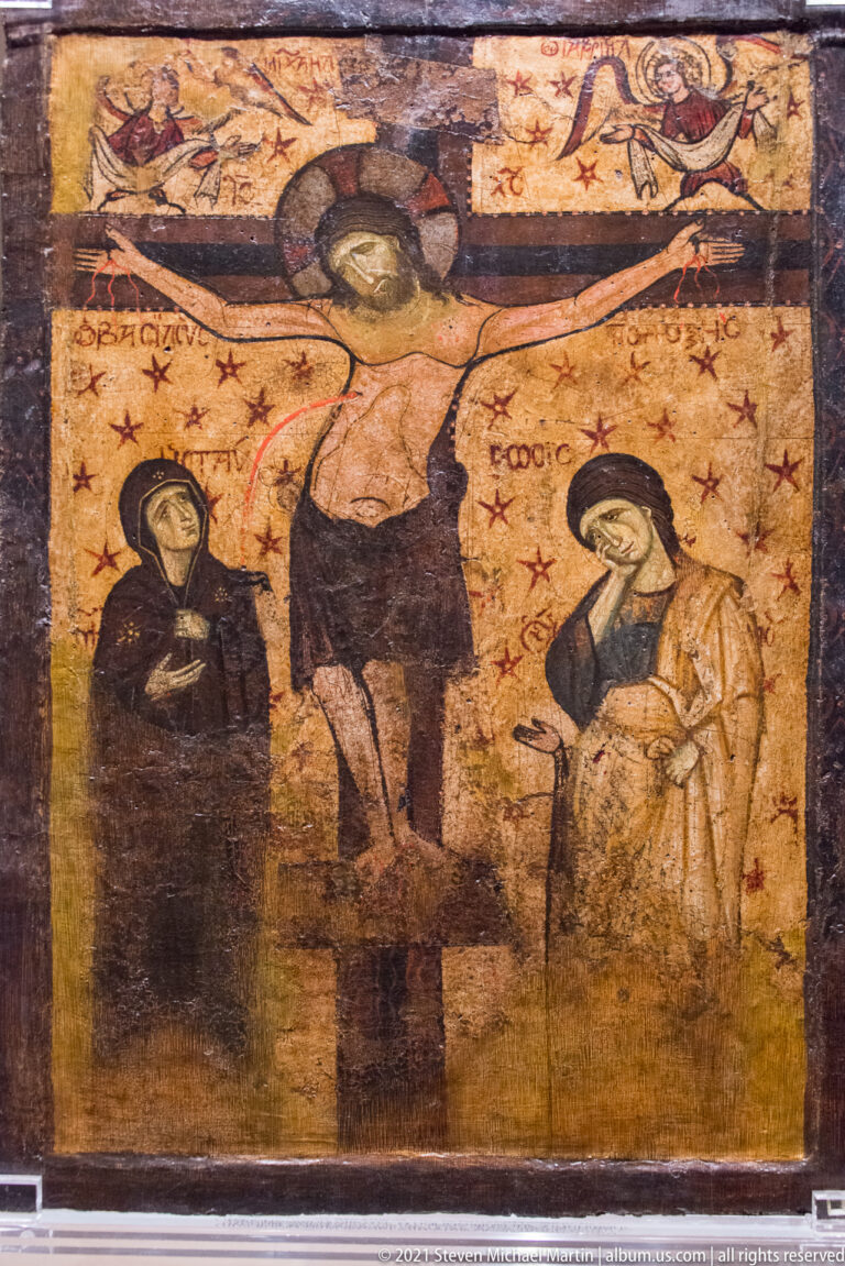 Painted Crucifixion with Christ on the cross and mourning figures standing on both sides.