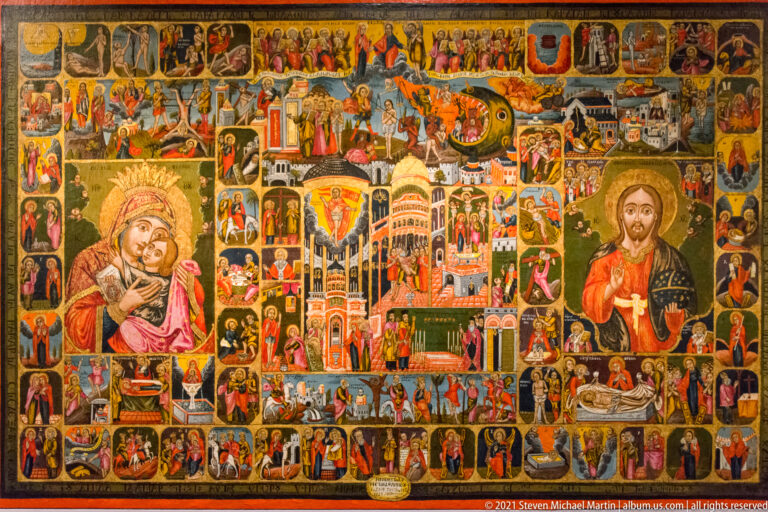 Large colorful composite icon filled with dozens of small religious scenes around larger figures of the Virgin and Christ and a central church scene.