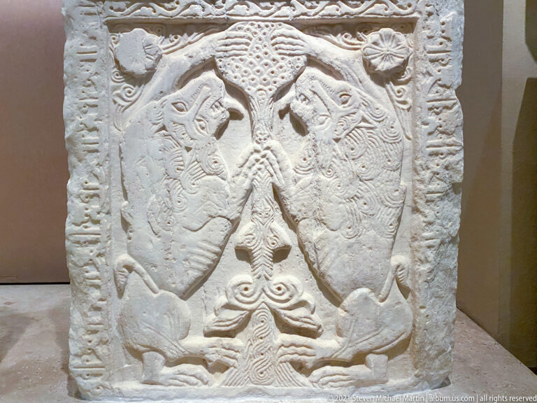 Rectangular marble panel with two confronted animals flanking a stylized tree, framed by carved borders and rosettes.