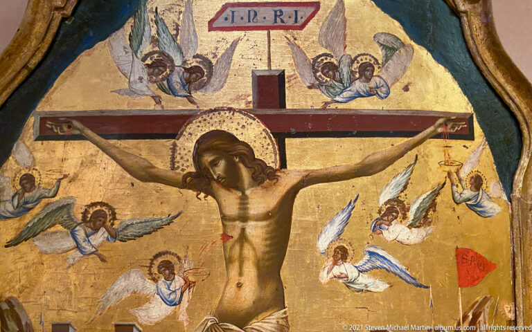Gold-ground Crucifixion icon with Christ on the cross and small angels surrounding the upper half of the scene.