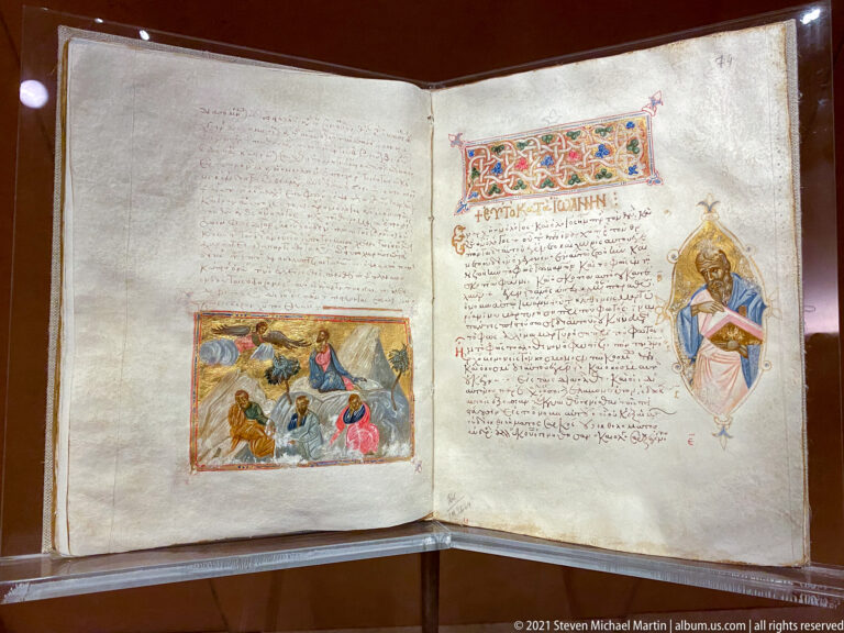 Open Greek manuscript with handwritten text, a rectangular miniature, decorated headpiece, and a haloed figure.