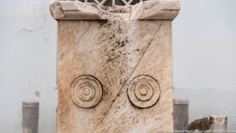 Weathered upright stone stele with two concentric circular carvings near the top and faint inscription below.