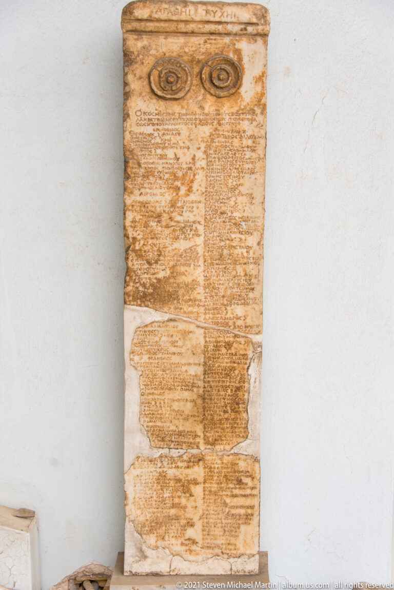Tall weathered stone stele with two circular carvings at top and several fields of faint inscription below.