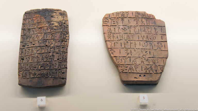Two brown clay tablets with rows of incised linear signs displayed side by side.