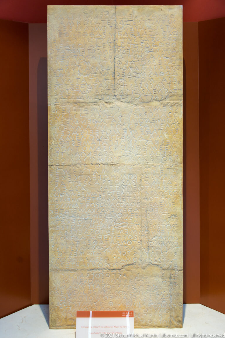 Large pale rectangular stone slab covered with dense, faint horizontal lines of inscription.