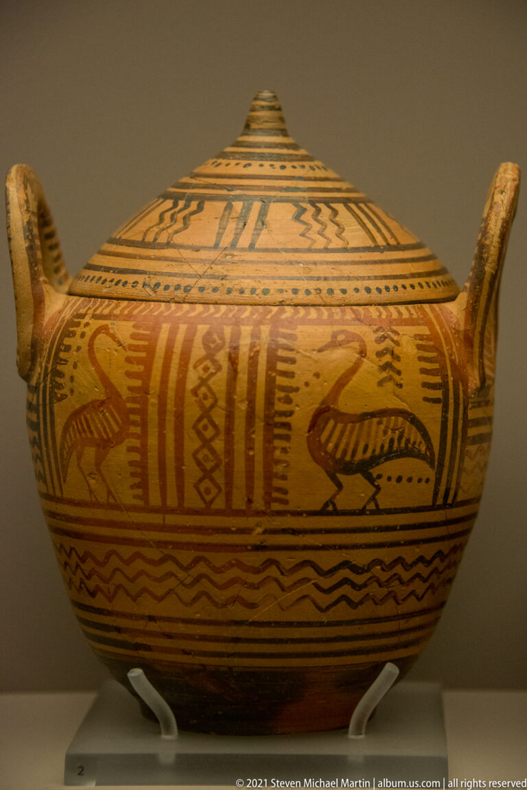Large lidded ceramic vessel with two upright handles, painted birds, zigzags, bands, and geometric ornament.