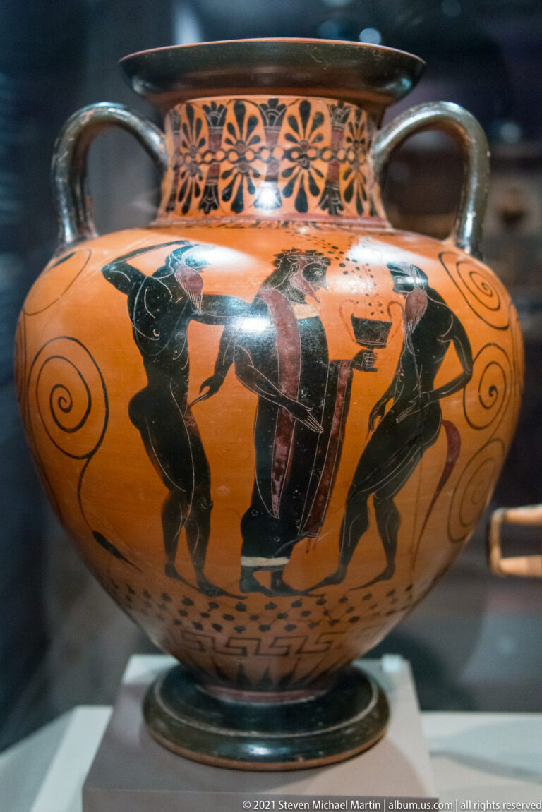 Wide two-handled black-figure vessel with human figures, side spirals, and a floral band beneath the rim.