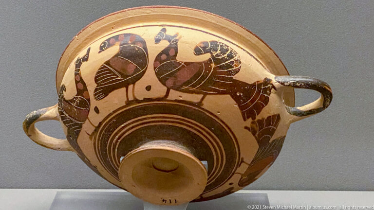 Shallow two-handled cup with two dark painted figures facing each other and concentric rings around the foot.