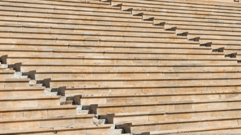 Close detail of diagonal stairways cutting across rows of weathered marble benches at the Panathenaic Stadium.