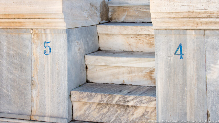 Close view of marble steps and seat blocks marked with blue numbers 5 and 4.