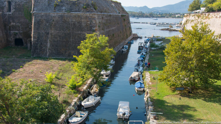 Contrafossa sea ditch beside the Old Fortress, with small boats moored between massive stone fortification walls.