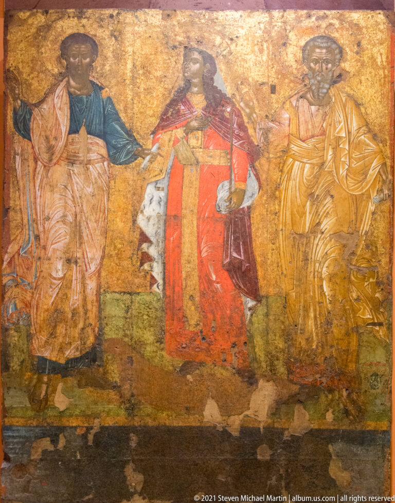 Religious panel with several standing and seated figures in red, blue, and ocher garments against a gold background.