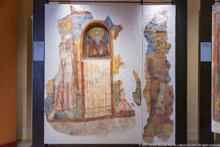 Conserved fresco fragment with central haloed figure in an arch and partial standing saints on either side.