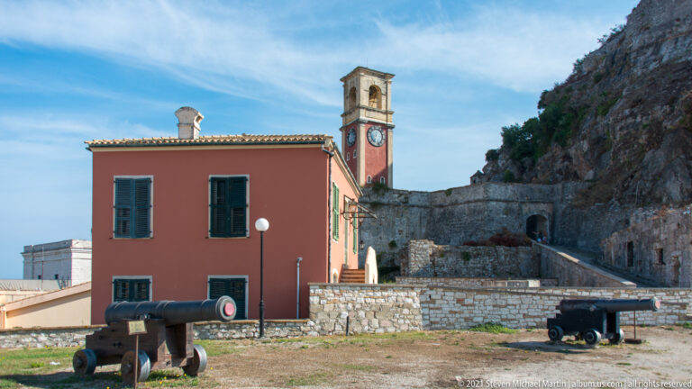 Historic cannons on grass below the 1848–1850 British clock tower and a shuttered fortress building.