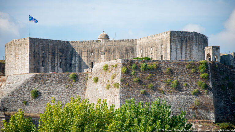 Close view of the New Fortress of Corfu with towering weathered bastion walls above a sloping stone revetment.