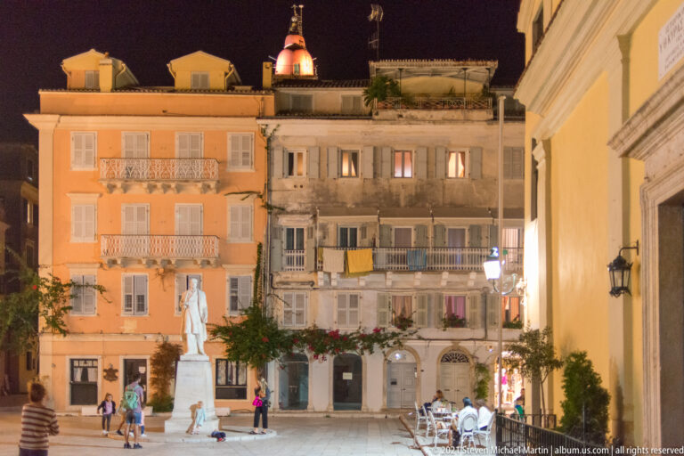 Night view of Heroes of Cypriot Struggle Square with the statue of Georgios Theotokis and historic residential façades.