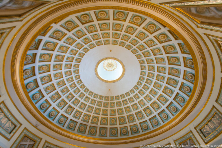 Upward view of the Rotunda’s concentric blue-and-gold coffered dome surrounding a circular central opening.
