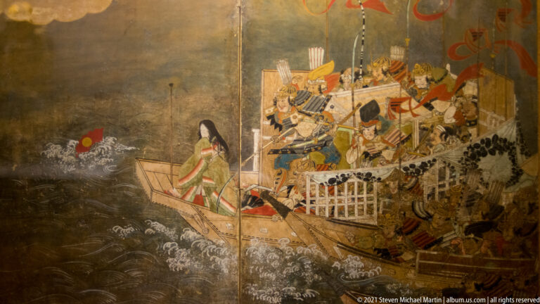 Japanese painting of a boat crowded with armored warriors on dark waves, with a seated woman near the bow.