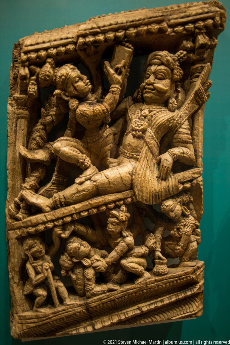 Deeply carved South Indian wooden chariot panel with intertwined Hindu figures, attendants, jewelry, and vigorously undercut limbs.