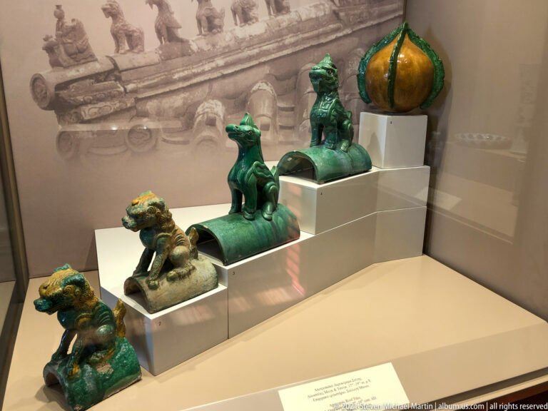 Green-glazed ceramic roof ornaments on stepped plinths, including guardian animals, upright mythical creatures, and a bulbous finial.