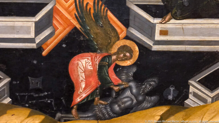 Winged archangel in red bends over a dark prostrate demon against a black ground and angular architecture.