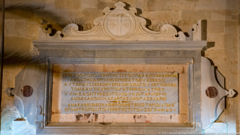 Greek inscription on a rectangular marble tablet framed by carved pilasters, scrollwork, and an ornate pediment.