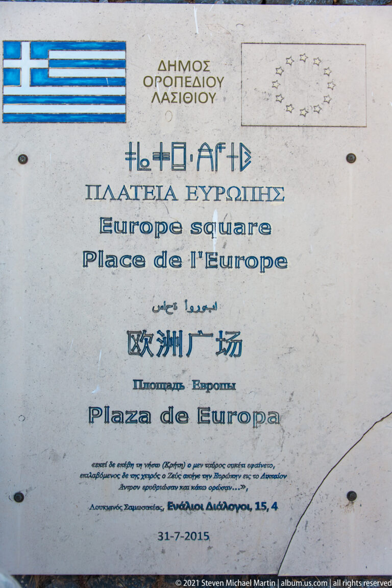 Stone plaque reading Europe Square in several languages beneath the Municipality of Lasithi Plateau heading and EU emblem.