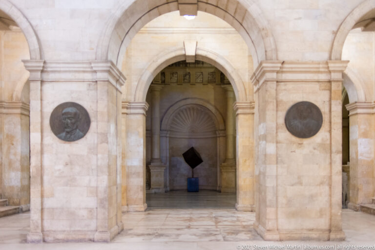 Stone arch inside the Heraklion Loggia with circular relief medallions and a shell-shaped niche visible beyond.
