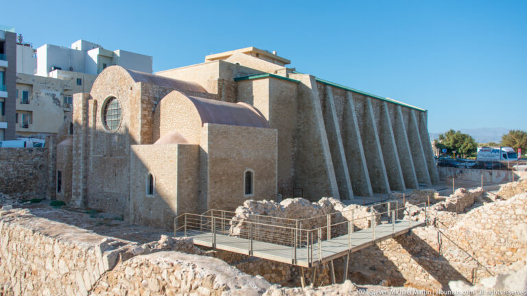 Stone Church of Saint Peter of the Dominicans with buttresses, rounded apses, circular window, and archaeological ruins crossed by a metal walkway.