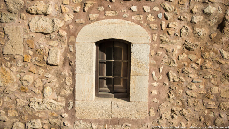 Small arched window with pale cut-stone surround set into rough rubble masonry at Saint Peter of the Dominicans.