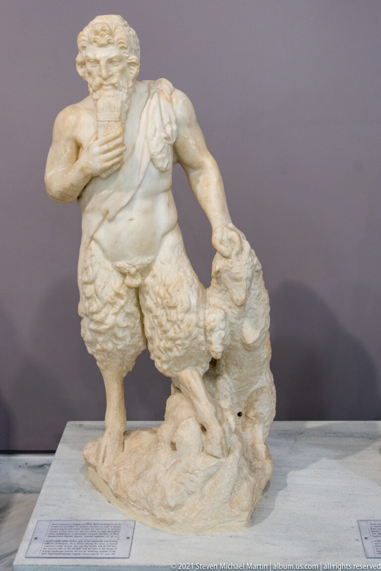 Fragmentary marble statue of a muscular bearded male wearing a shaggy garment and standing beside a smaller animal form.