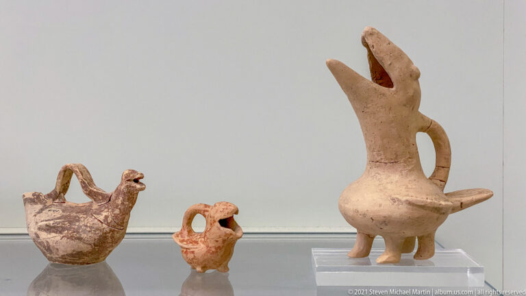 Three terracotta bird-shaped vessels, including two small rounded examples and a tall long-necked vessel with open beak.