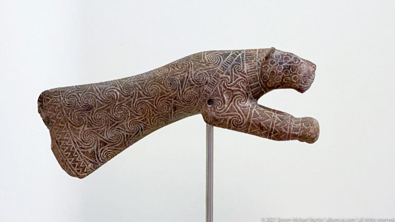 Long forked stone object densely incised with spirals, circles, crosshatching, and geometric patterns.