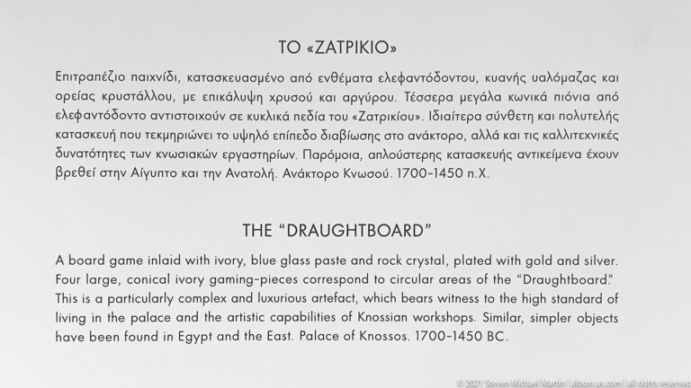 Bilingual museum label titled “The Draughtboard,” describing its materials, gaming pieces, Palace of Knossos provenance, and date.